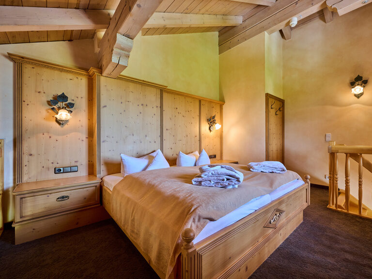 Das große gemütliche Doppelbett in der luxuriösen Prinz Luitpold Suite mit viel Holzmobiliar im Hotel Happinger Hof in Bayern