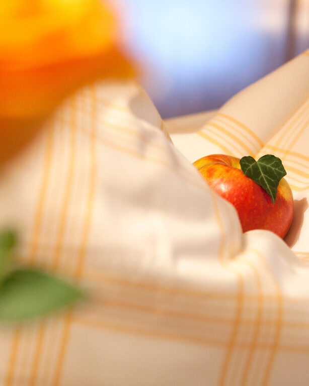 Nahaufnahme Apfel, auf dem Minzblatt liegt auf gestreifter Bettwäsche in Hotelbett