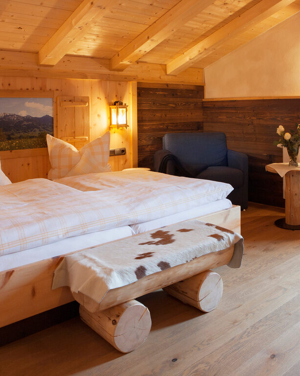 Das einladende Schlafzimmer mit Doppelbett und Möbeln im Landhausstil im Hotel Happinger Hof in Rosenheim