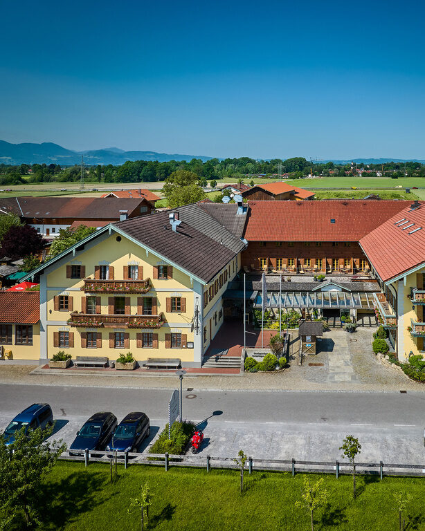 Die Vorderseite des Hotels Happinger Hof in Bayern aus der Luftansicht an einem sonnigen Tag