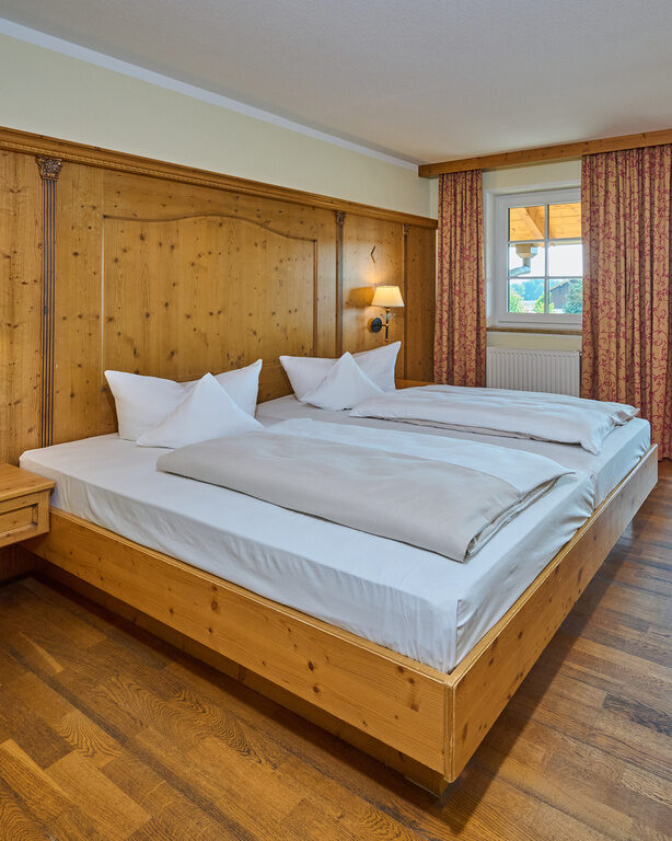Der möblierte Schlafensbereich mit Doppelbett in einem Hotelzimmer des Landhotels Happinger Hof in Oberbayern