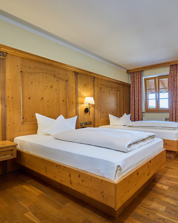 Ansicht eines geräumigen  Hotelzimmers im Landhausstil mit gemütlichen Holzmöbeln