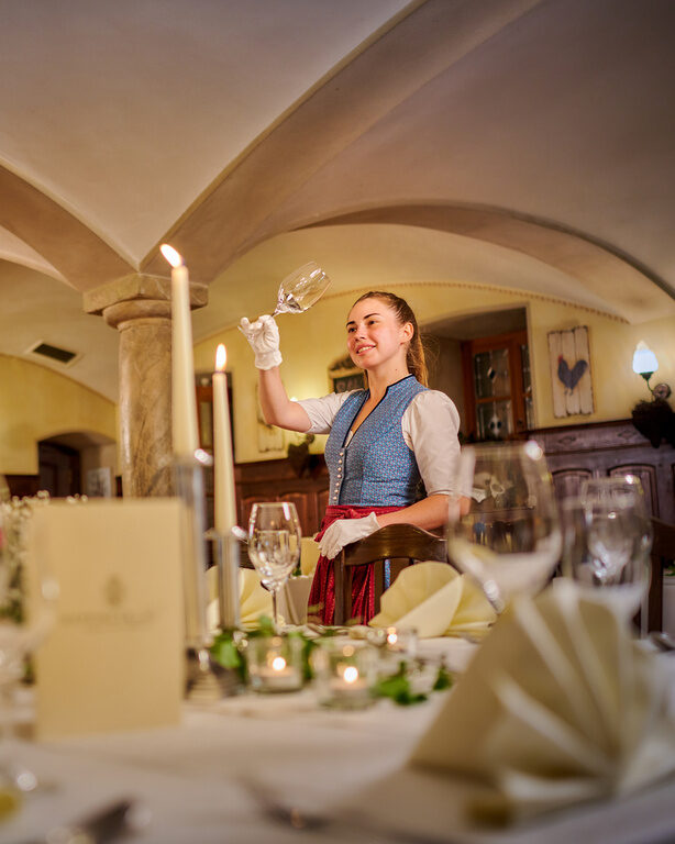 Bedienung hält Weinglas in der Hand und steht vor gedeckten Tisch für Feierlichkeit
