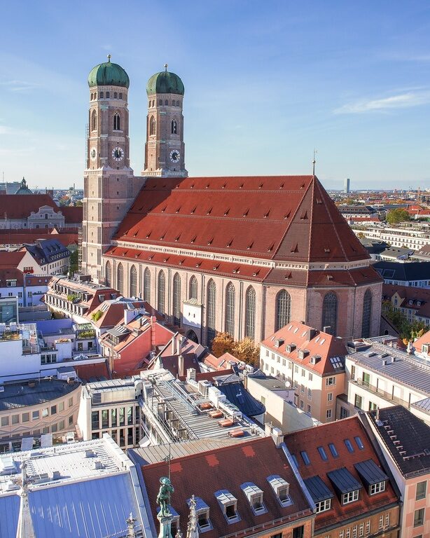 Sonniger Tag vor einer imposanten Kirche in München, umgeben von zahlreichen Stadthäusern