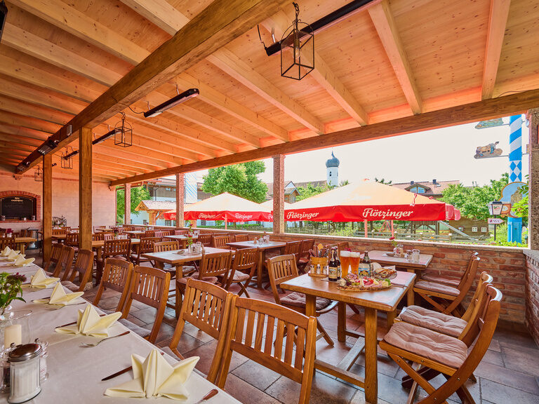 "Festlich gedeckte Bankett-Terrasse mit einer großen Brotzeitplatte auf einem weiteren Tisch, umgeben von Sonnenschirmen