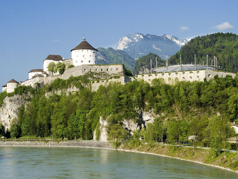 Historische Festung in Österreich, Salzburg auf Felsen, davor Fluss, im Hintergrund Gebirge