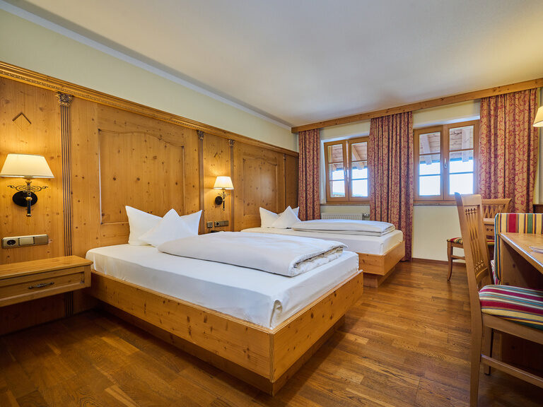Ansicht eines geräumigen  Hotelzimmers im Landhausstil mit gemütlichen Holzmöbeln