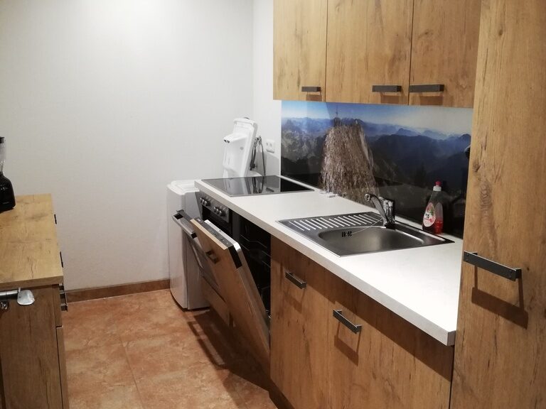 Moderne Küche mit Holzelementen und Berg-PanoramaBild, daneben Waschmaschine