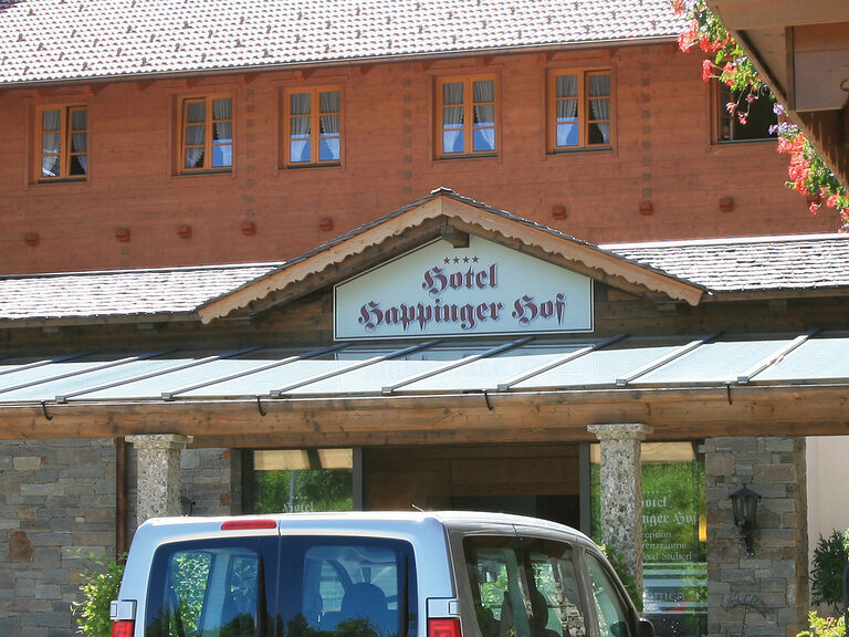 Ein Schild mit dem Logo des Hotels Happinger Hof über dem Eingang zum Landgasthof in Rosenheim