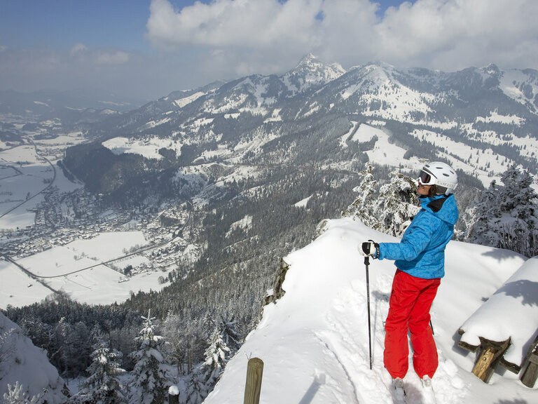 Skifahrerin steht an Hang mit Panorama auf Rosenheim von oben im Winter