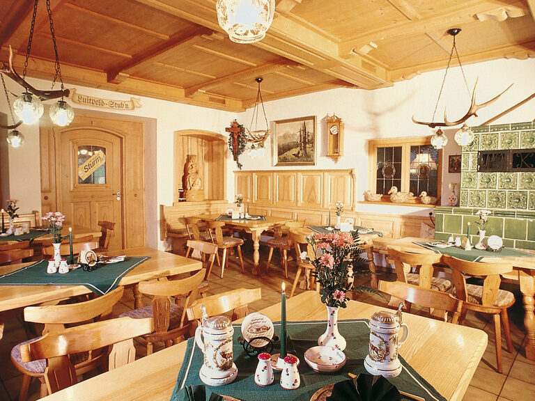 Traditionelles, bayerisches Bräusüberl mit Kachelofen und Holztischen und -stühlen
