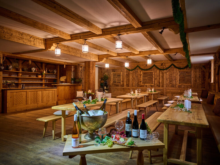 Ein zünftiger Festsaal im Hotel Happinger Hof in Rosenheim mit gedeckten Tischen und Ausstattung aus Holz
