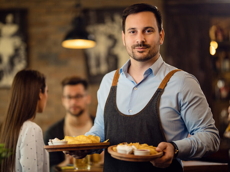 Eine Bedienung im Happinger Hof in Oberbayern bringt zwei Gerichte zu Tische.