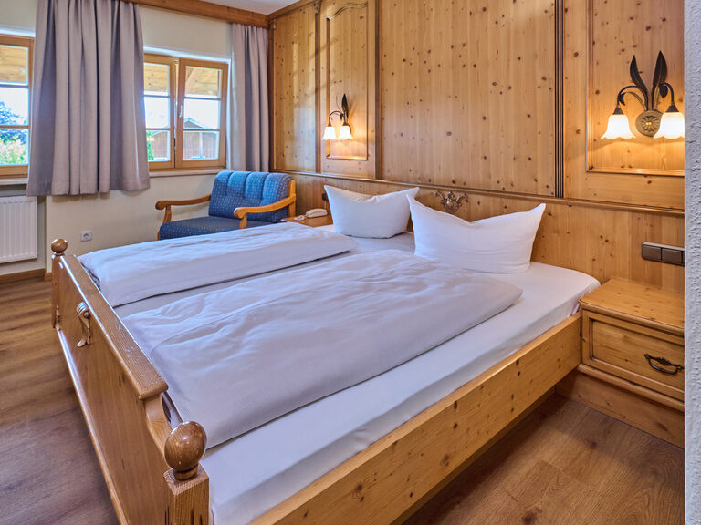 Die Betten in einem Doppelzimmer das im Landhausstil gehalten ist mit viel Holzmobiliar