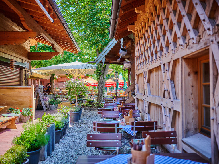 Ein Blick in den Biergartes des Happinger Hofs mit mehreren Tischen und Stühlen