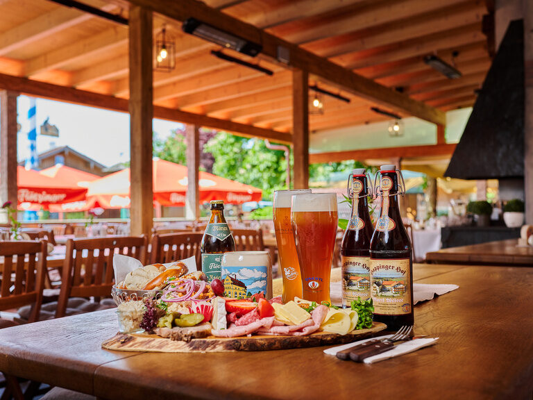 Brotzeitplatte im Biergarten im 3-Sterne-S-Hotel und Landgasthof Happinger Hof in Rosenheim Große Brotzeitplatte auf Tisch in Biergarten, mit Weizengläsern, Brotkorb, Aufstrichen, Käse und Wurst