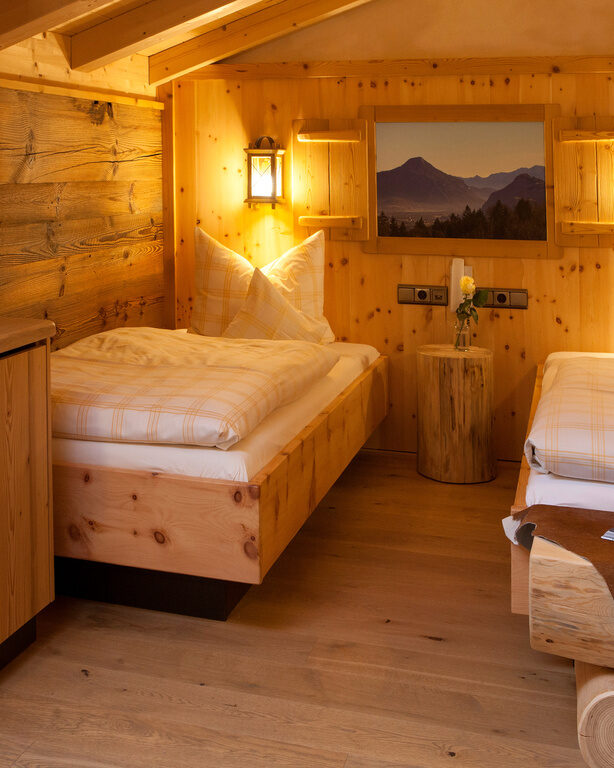 Das Schlafzimmer im Kranzhorn Twinbettzimmer mit voller Holzausstattung und gemütlicher Beleuchtung
