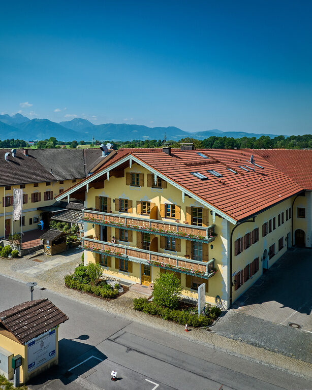 Seitliche Drohnenaufnahme von Dreiseithof an sonnigem Tag mit Alpen im Hintergrund