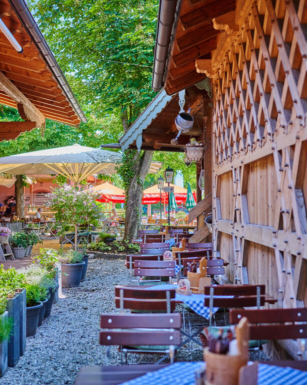 Ein Blick in den Biergartes des Happinger Hofs mit mehreren Tischen und Stühlen