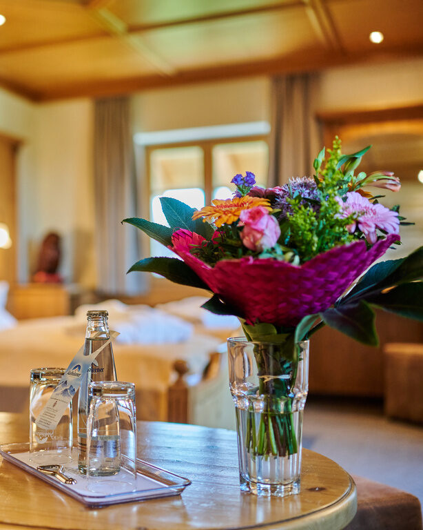 Auf einem kleinen Holztisch in einem Hotelzimmer des Happinger Hof in Rosenheim steht ein Strauss Blumen
