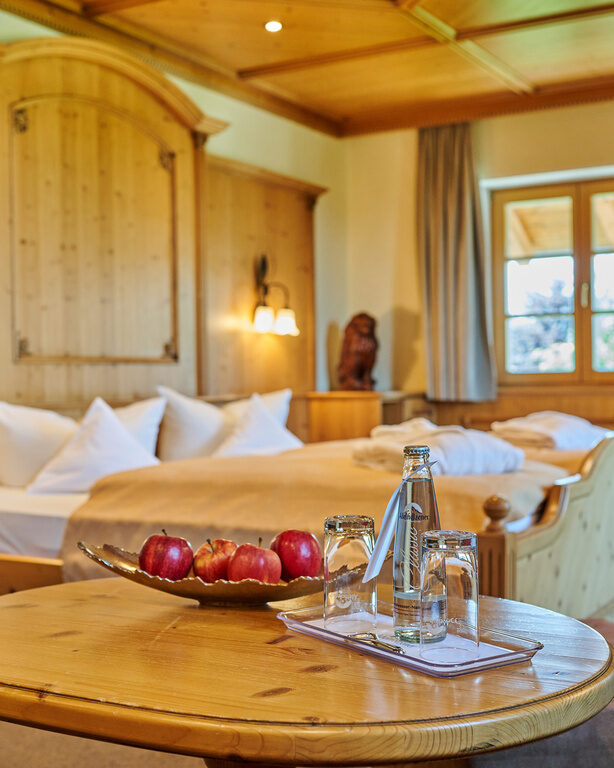 Ein Abstelltisch im Hotelzimmer, auf dem eine Schale mit Äpfeln sowie ein Wasserflasche mit Gläsern stehen