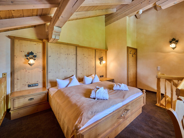 Doppelbett in Obergeschoss von Galerie mit Holzfassade, darauf zwei Bademäntel