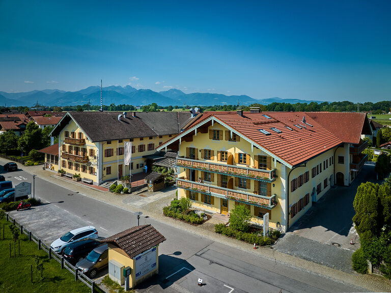 Seitliche Drohnenaufnahme von Dreiseithof an sonnigem Tag mit Alpen im Hintergrund