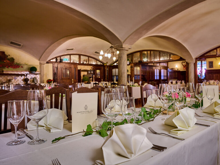 Eingedeckter Tisch mit Serviettenformen, Weingläsern und Blumen