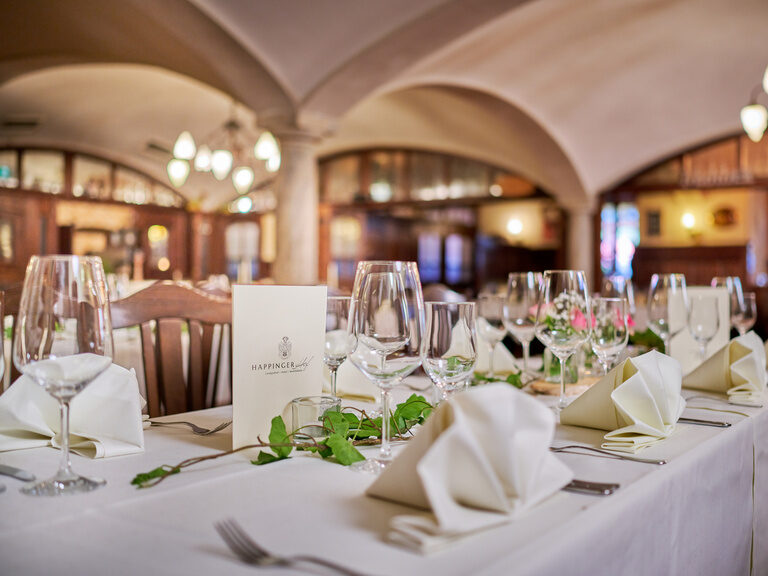 Eingedeckter Tisch mit Serviettenformen, Weingläsern und blumen