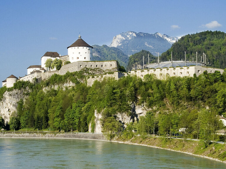 Festung Hohensalzburg nahe dem 3-Sterne-S-Hotel und Landgasthof Happinger Hof beim Chiemsee Historische Festung in Österreich, Salzburg auf Felsen, davor Fluss, im Hintergrund Gebirge