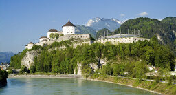 Im Sommer zeigt sich eine mittelalterliche Festung in Kufstein vor einer malerischen Flusslandschaft, umgeben von majestätischen Bergen