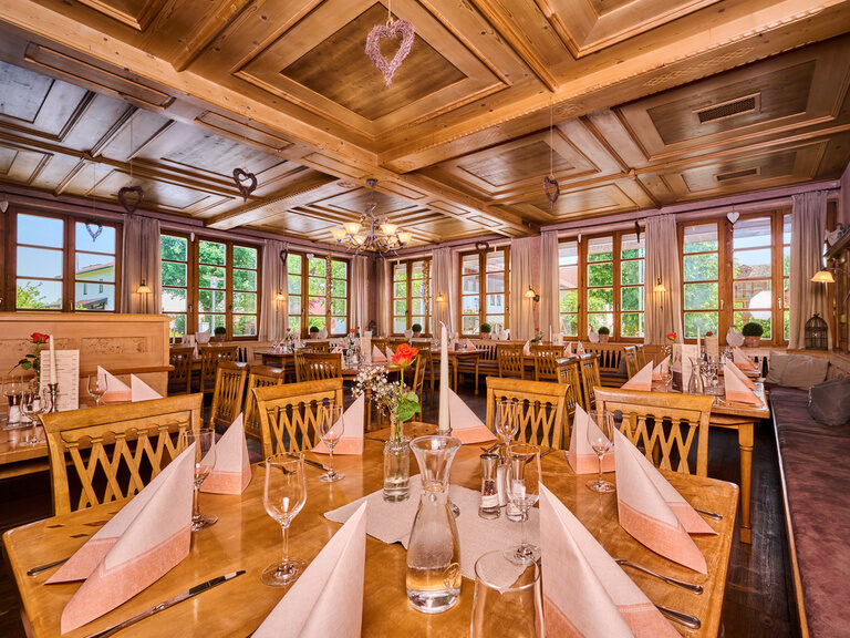 Mehrere feierlich gedeckte Tische in einem einladenden Festsaal im Hotel Happinger Hof in Oberbayern