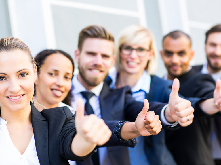 Glückliches Tagungsteam zeigen Daumen nach oben und lachen in Richtung Kamera