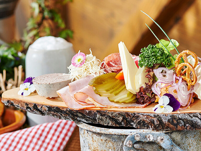 Holzplatte mit Brotzeit, verschiedenen Käsesorten Wurst und Gemüse