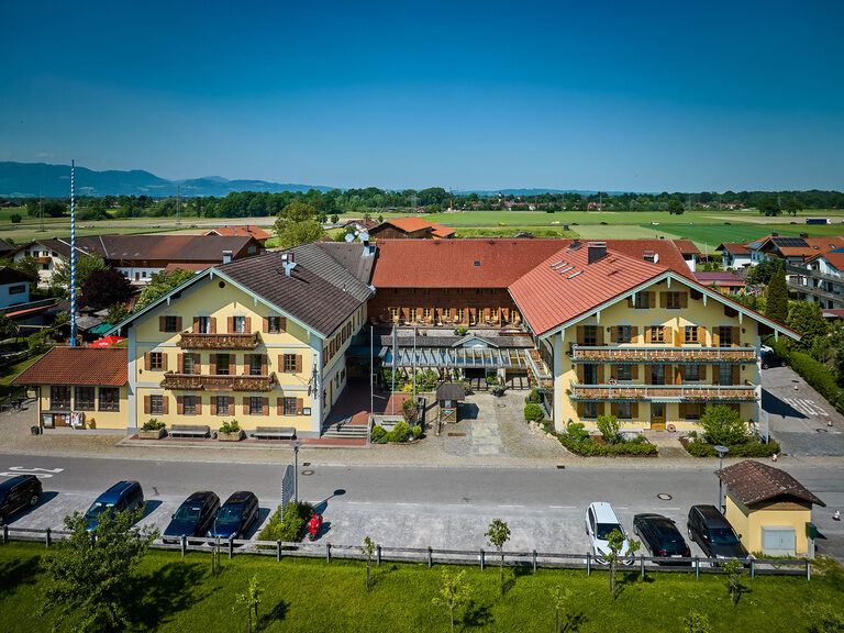 Die Vorderseite des Hotels Happinger Hof in Bayern aus der Luftansicht an einem sonnigen Tag