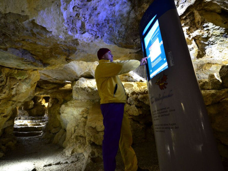 Ein Mann steht vor einem Monitor im Salzbergwerk Berchtesgaden, erkundet die Geschichte und die Geheimnisse