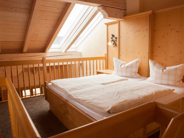 Das gemütliche Doppelbett der Prinz Luitpold Suite im Happinger Hof mit hellem Dachfenster