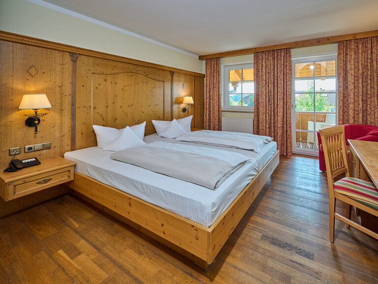 Der möblierte Schlafensbereich mit Doppelbett in einem Hotelzimmer des Landhotels Happinger Hof in Oberbayern