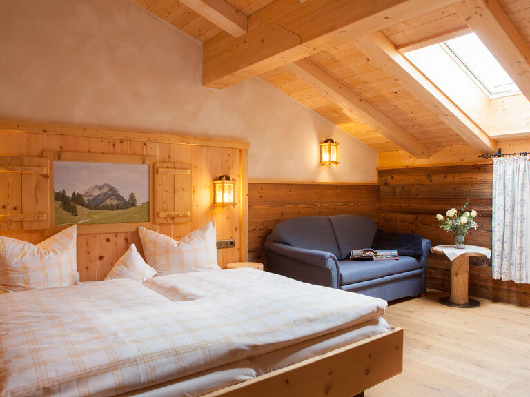 Das helle Schlafzimmer im Heuberg Doppelzimmer des Hotels Happinger Hof mit Doppelbett und Dachfenster.