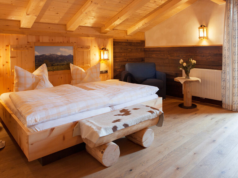 Das einladende Schlafzimmer mit Doppelbett und Möbeln im Landhausstil im Hotel Happinger Hof in Rosenheim