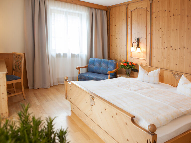 Das einladende, helle Schlafzimmer im Landgasthof Doppelzimmer mit verschiedenen Holzmöbeln und gemütlichen Doppelbett