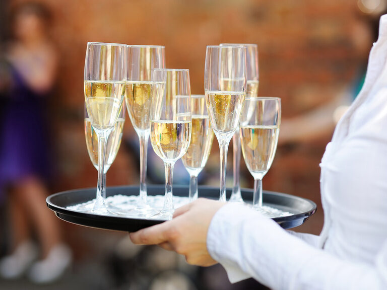Nahaufnahme von Sektgläsern, die auf Tablett getragen werden