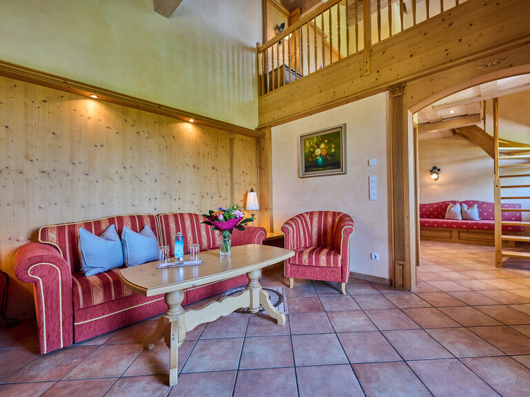 Gestreiftes, elegantes Sofa mit passendem Sessel, davor kleiner Tisch mit Wasserflasche, Gläsern und Blumenvase