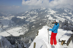 Skifahrerin steht an Hang mit Panorama auf Rosenheim von oben im Winter