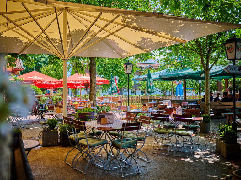 Traditioneller Biergarten mit Holzklappstühlen und -tischen, Sonnenschirmen, Blumen