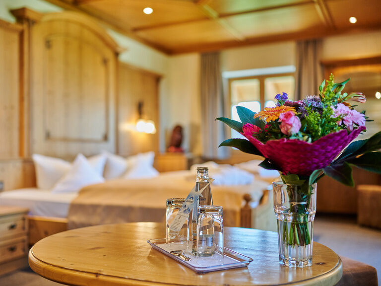 Traditionelles Hotelzimmer mit Holz-Einrichtung im Hotel Happinger Hof in Oberbayern Traditionelles Hotelzimmer mit Holz-Einrichtung und Balkon, und gemusterten Vorhängen
