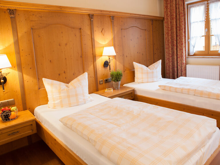Zwei Betten die nebeneinander stehen in einem gemütlichen Hotelzimmer im Happinger Hof in Rosenheim